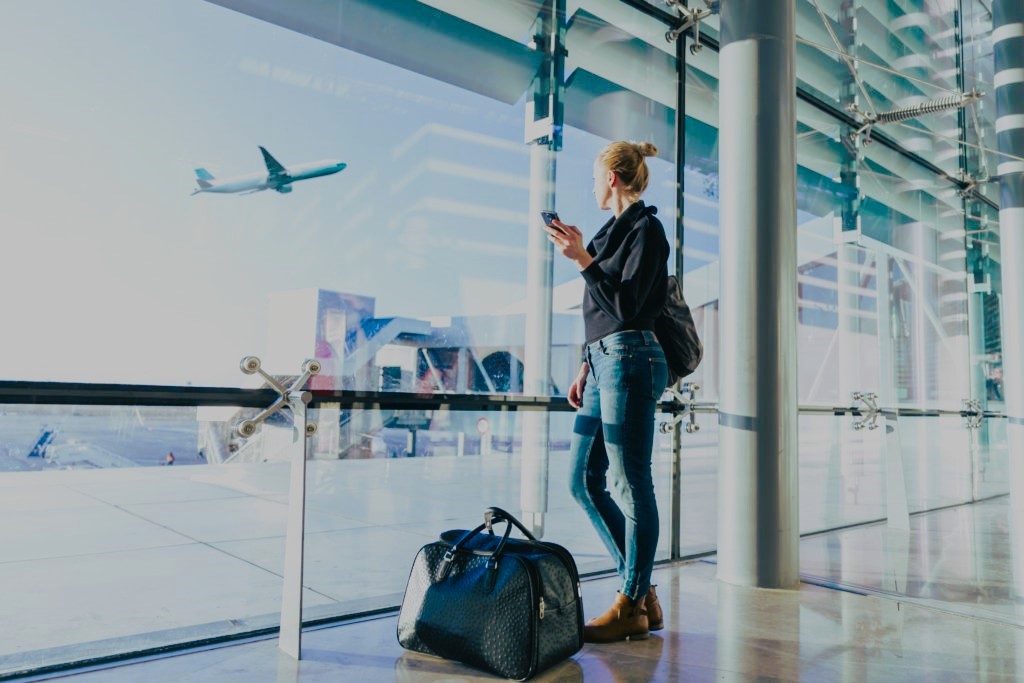 Chauffeur meeting passenger inside arrivals with signboard